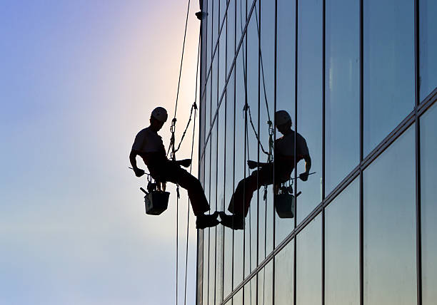 Silhouette of a man cleanign the windows of a high-rise building